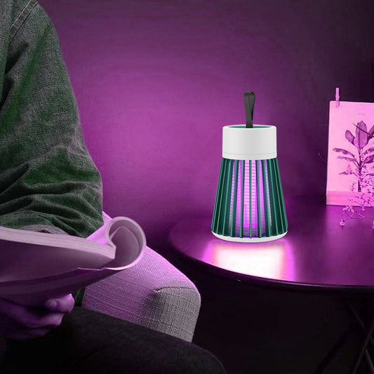 Person sitting on a couch with a purple book, holding a remote control, next to a small lamp on a table with a purple background.